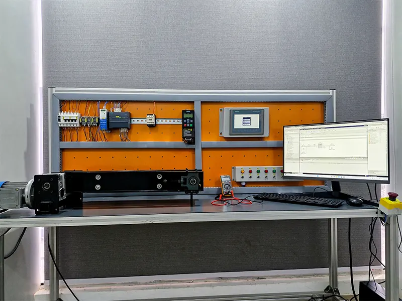 A PLC training workstation equipped with PLC panel, HMI screen, relays, a conveyor system with a motor, push buttons, and a computer displaying PLC programming software.